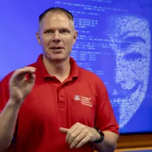 White male teacher wearing red shirt in front of blue screen